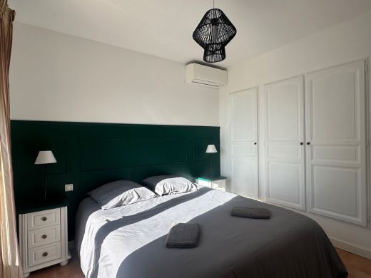 Chambre au rez-de-chaussée avec lit double de 160 cm, armoire intégrée, commode et accès direct à la terrasse, offrant un espace confortable et pratique.