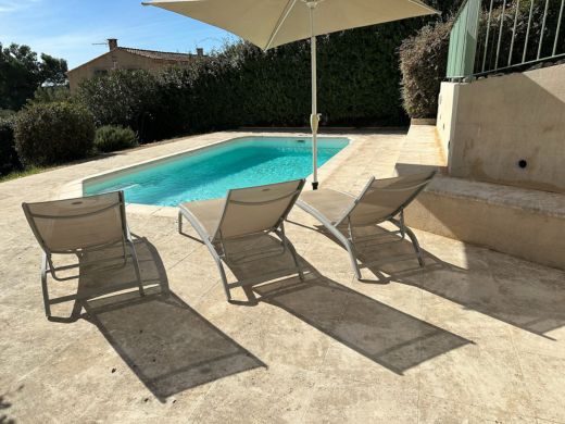 Piscine extérieure privée de la villa à louer en Provence à Paradou, entourée de transats, d'une terrasse en pierre et de végétation méditerranéenne.